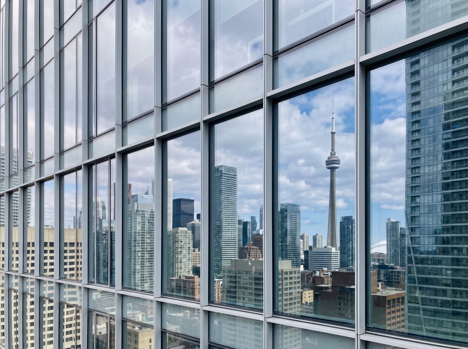 Downtown Toronto glass curtain wall with aluminum mullions reflecting the CN Tower