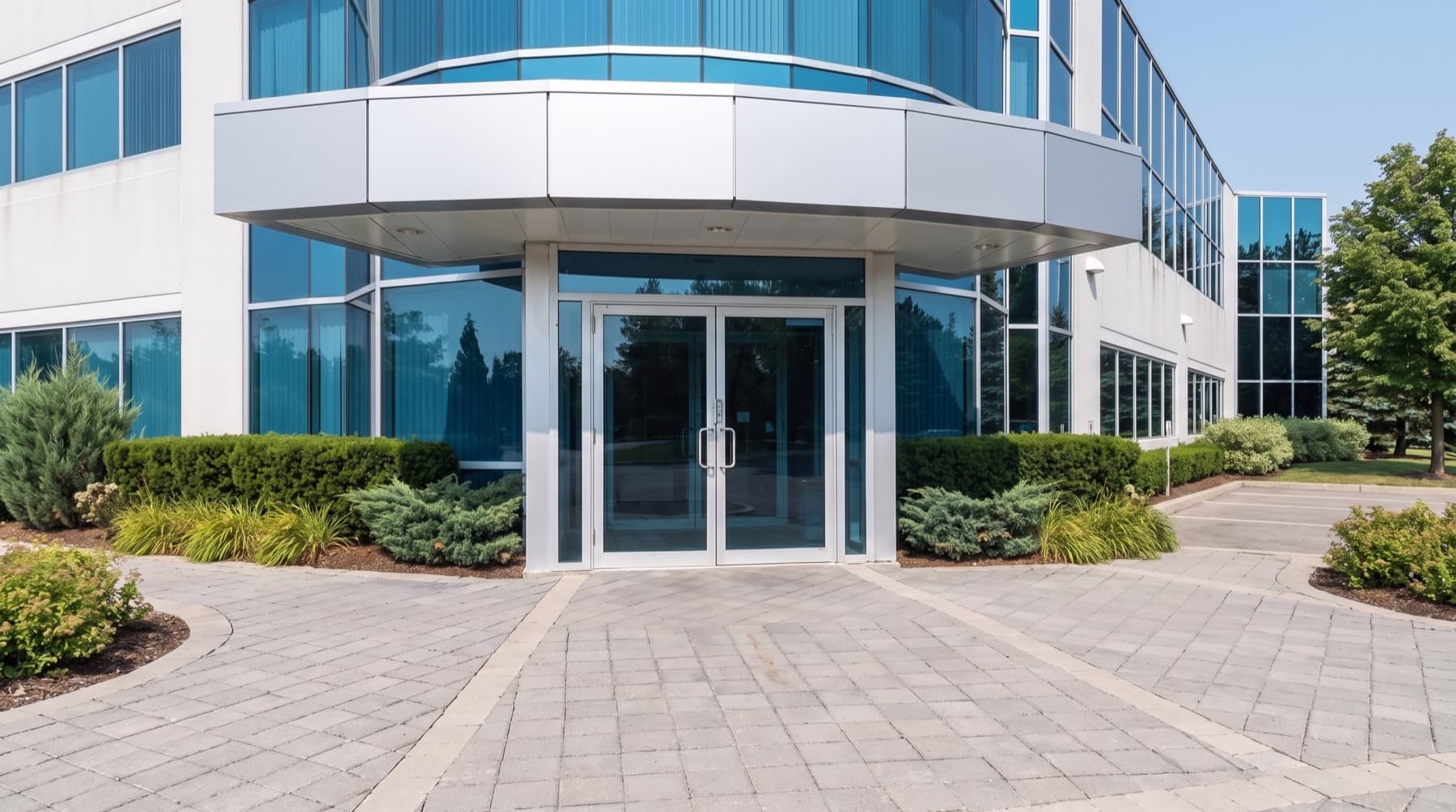 Modern Mississauga-style commercial office entrance with aluminum glass doors and blue-tinted storefront glazing