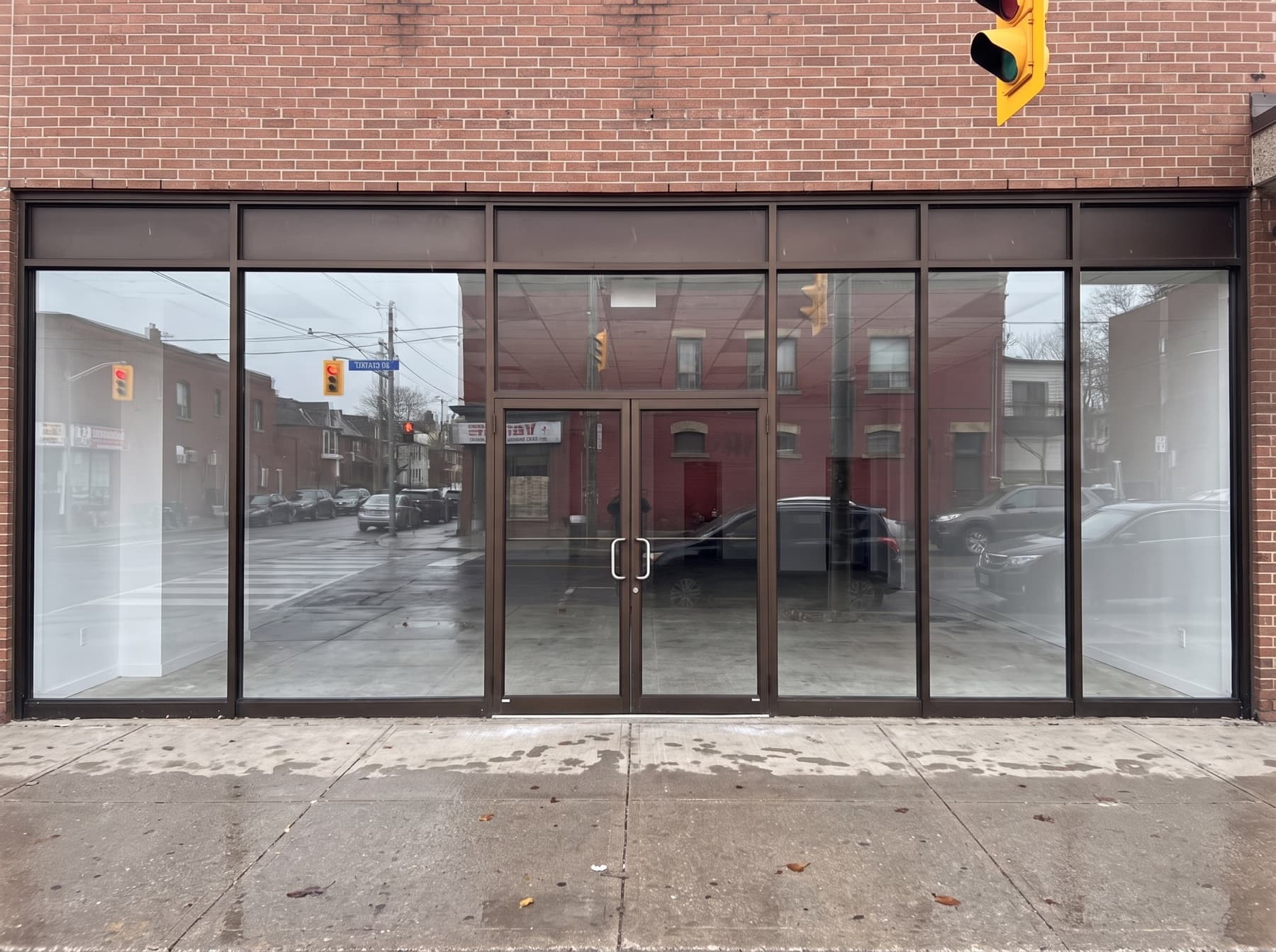 Toronto Dundas Street West style brick storefront with dark aluminum framing and tempered glass